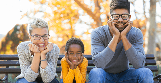 A smiling family poses for a photo on a park bench.