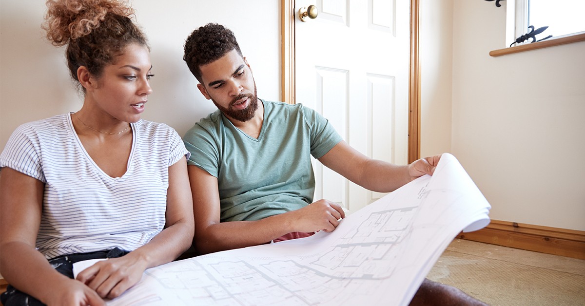 A couple looks at the blueprints of a house for a remodeling project.
